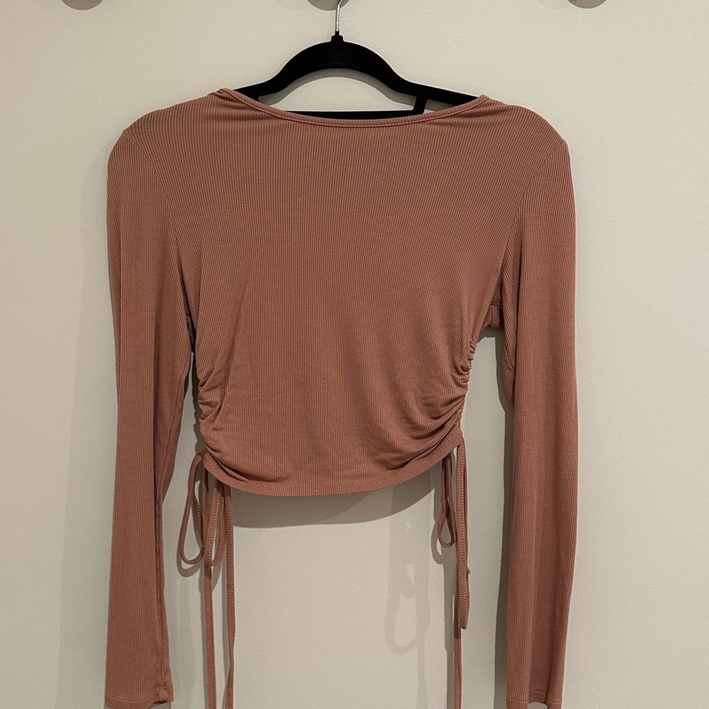 Cropped long sleeve top cinches and ties at the sides